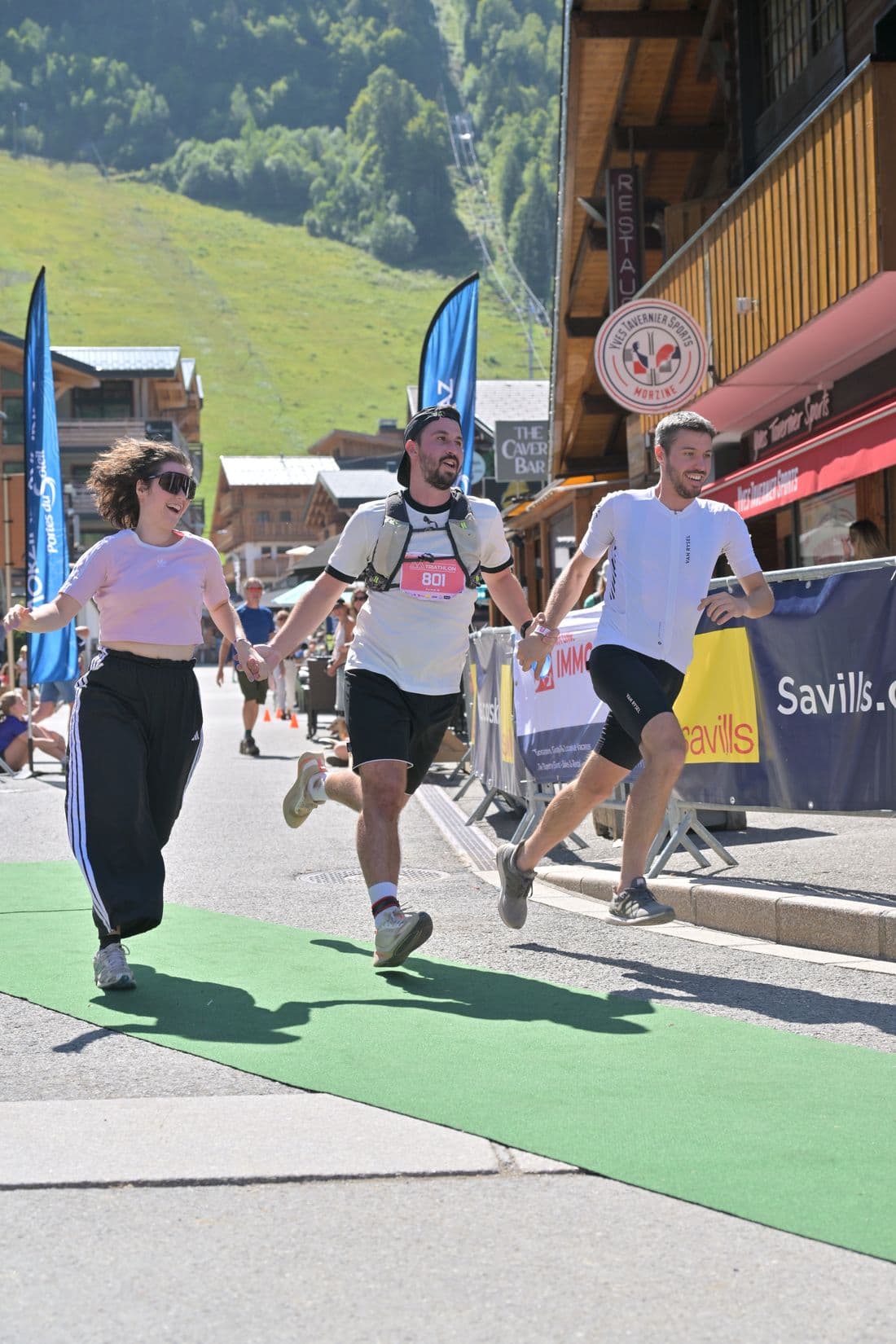 Trois finishers d’un triathlon main dans la main, un seul dossard visible, visages reconnus par PixTager